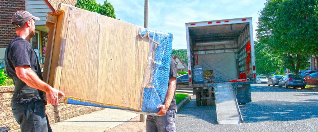 movers carrying a large item wrapped in brown paper