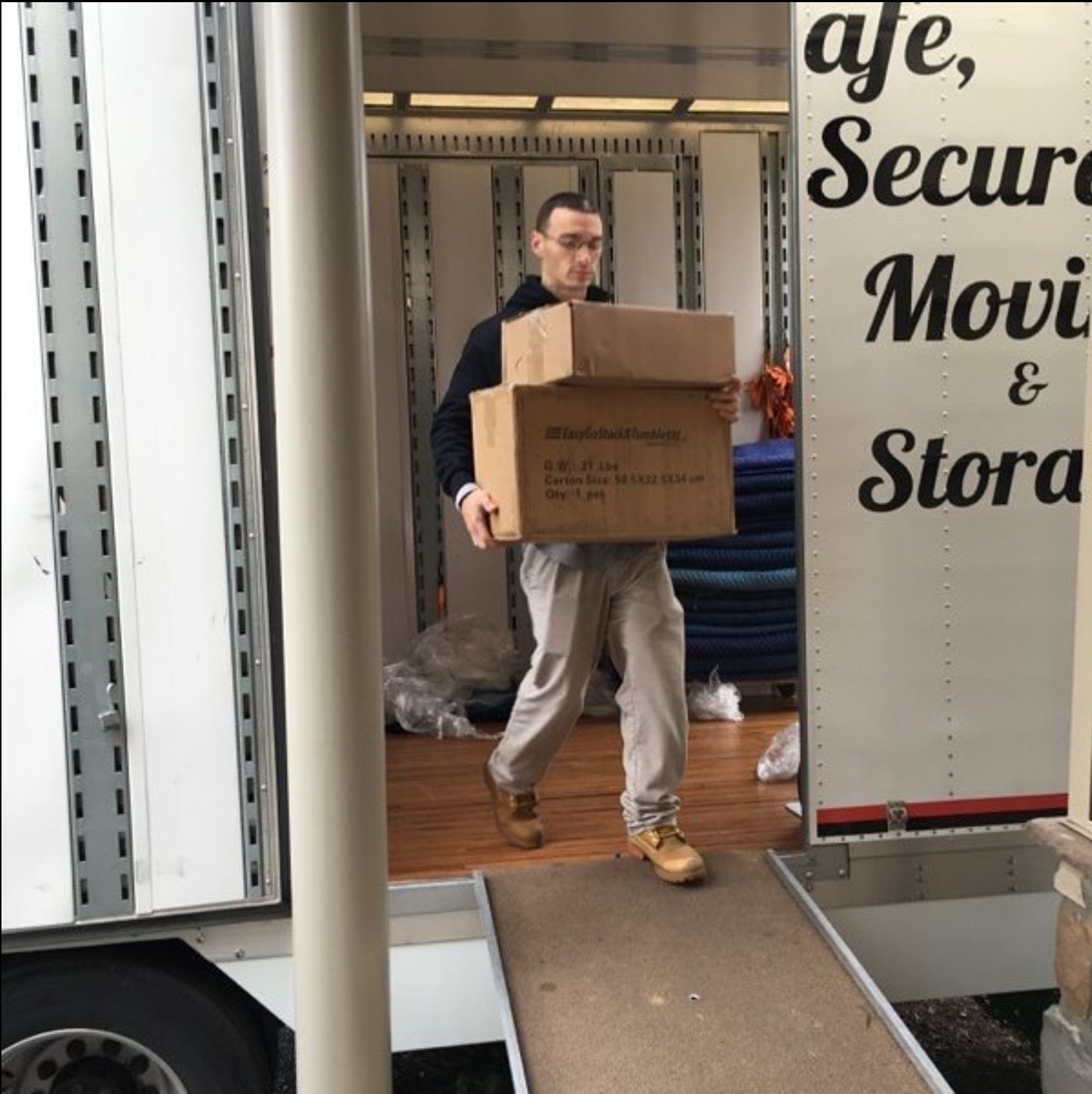 Man Carrying Boxes out of a moving truck