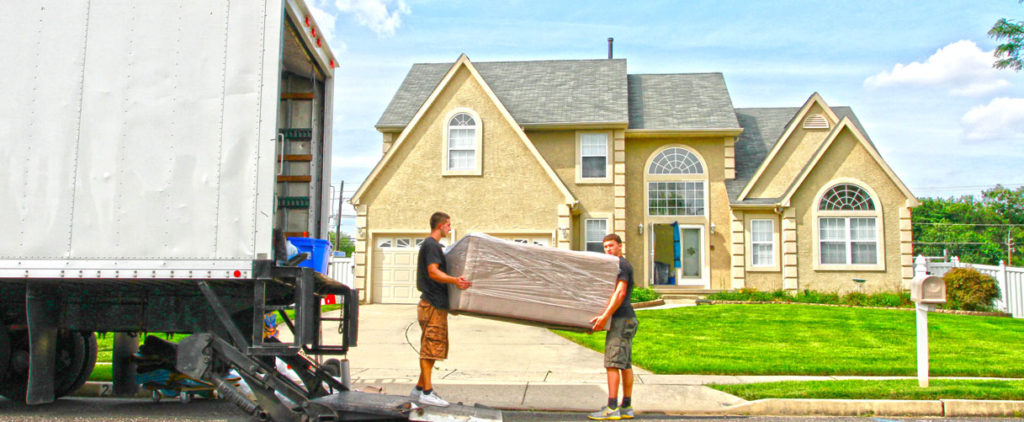 Movers unload a sofa into a new home.