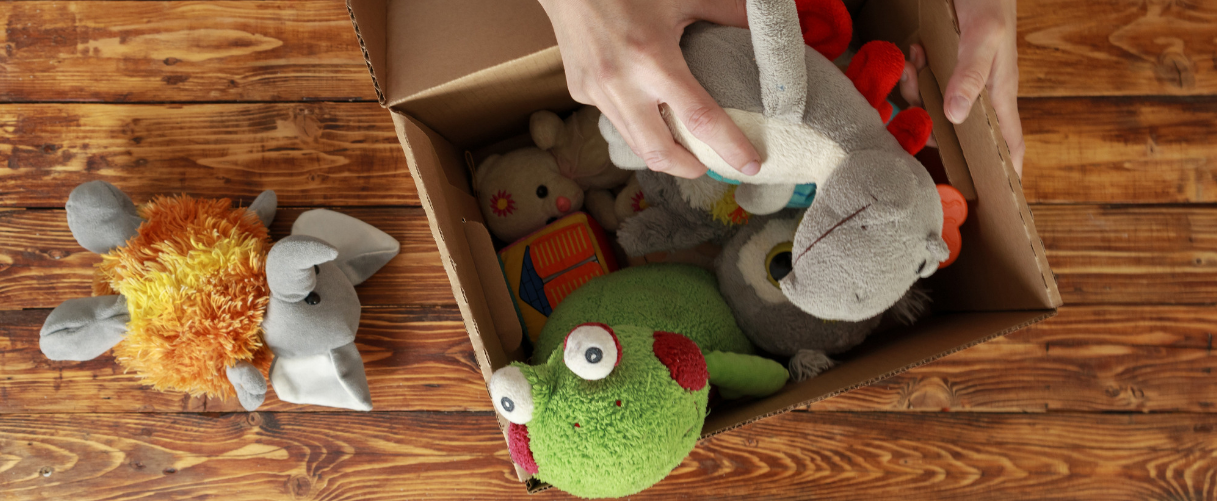 Person packing stuffed toys in a cardboard box