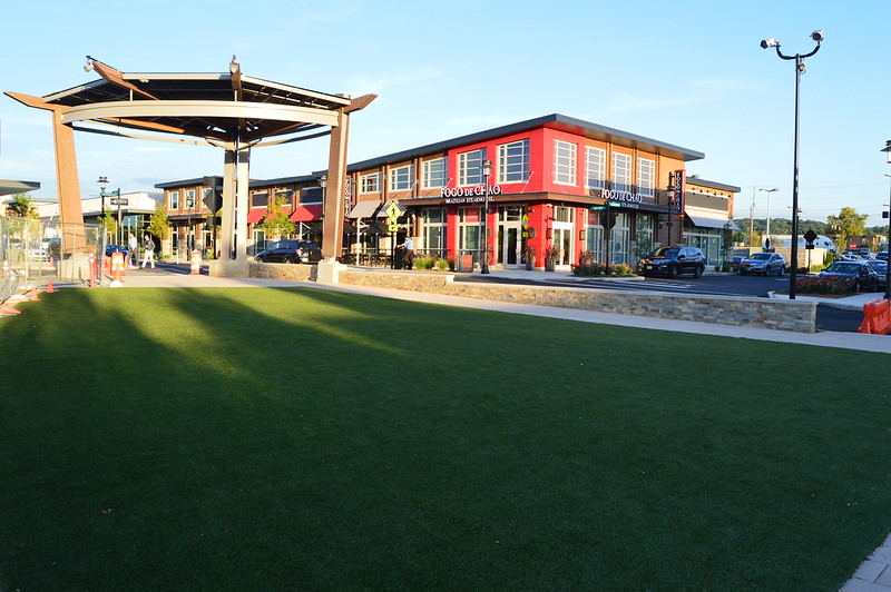 a shopping plaza with a green lawn and gazebo